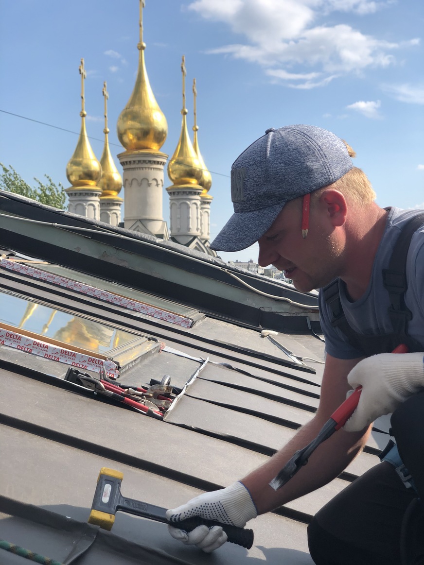 Feinschliff an einem Stehfalzdach in Kiew. Im Hintergrund die goldenen Kirchturmhauben