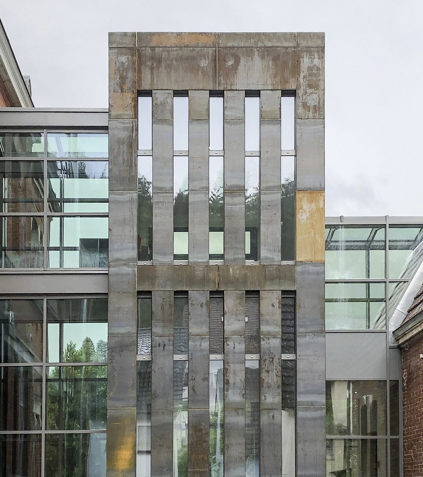 Die breiten, stahlbekleideten Lisenen erzeugen strenge vertikale Strukturen an der Fassade zur Straßenseite