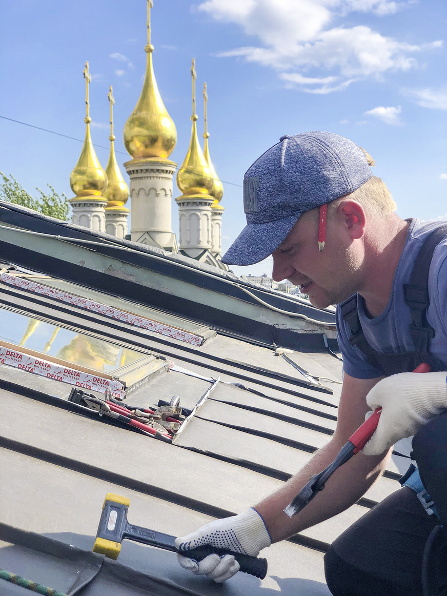 Feinschliff an einem Stehfalzdach in Kiew. Im Hintergrund die goldenen Kirchturmhauben