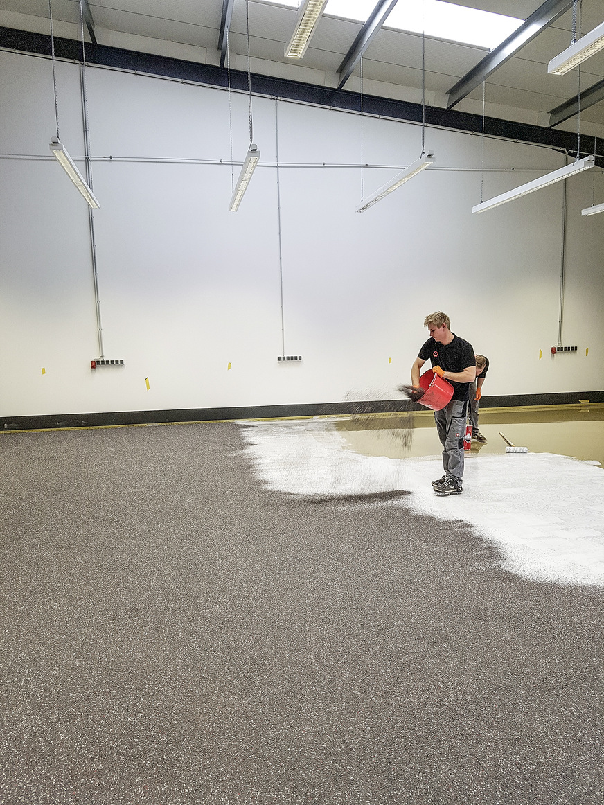 Mit Enke Betoncoat kann nahezu jeder Anforderungsschwerpunkt projektbezogen abgestimmt werden. Das Foto zeigt das Einstreuen der Farbchips