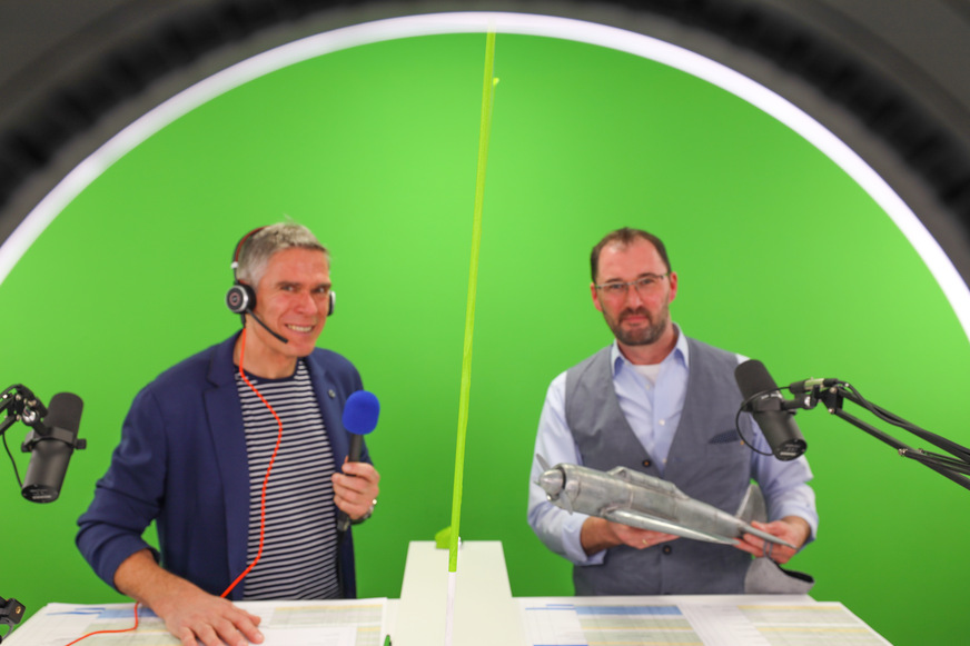 Studiogast Berthold Ruck (Rheinzink, r.) freut sich über den Titanzinkflieger vom BAUMETALL-Workshop