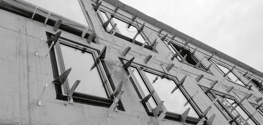 Die Einhaltung örtlicher Brandschutzbestimmungen erforderte den Verzicht auf die ursprünglich vorgesehene Holzschalung als Unterkonstruktion. Stattdessen wurde der hinterlüftete Wandaufbau mit weitestgehend wärmebrückenfreien Wandkonsolen, zwischengelegten Mineralfaserplatten und einer Tragschale aus Stahlblechprofilen realisiert