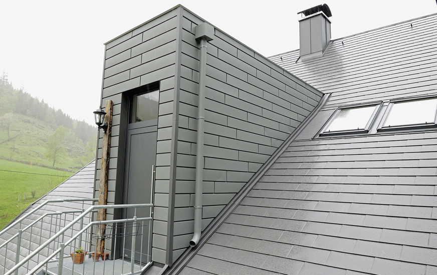 Der Eingangserker ist mit Aluminium-Hauspaneelen im Farbton Grau Pearls bekleidet, die Aluminium-Eckleisten sind im Farbton Hausgrau Pearls abgesetzt 