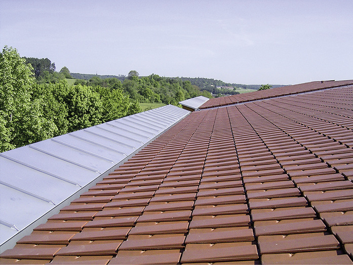 Ein Schmetterlingsdach, zwei Werkstoffe: Edelstahl und Tondachziegel