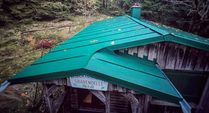 Die Hubertushütte im Thüringer Wald fügt sich mit ihrem moosgrünen Aluminiumdach gut in die Landschaft ein