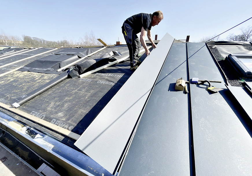 Die 5 m langen Scharen werden mit ­Winkelstehfalz- und -schiebehaften ­direkt in den integrierten Mehrschichtholzleisten der Dämmelemente befestigt