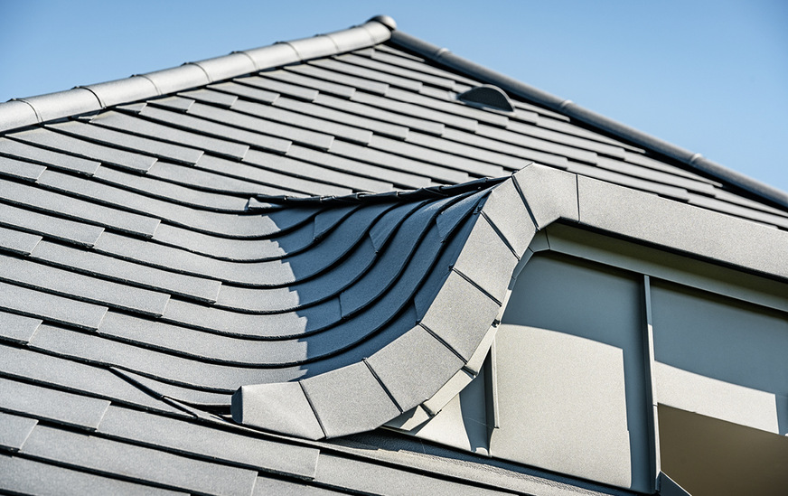 Die segmentiert ausgeführte Verblendung leitet Niederschlagswasser vom Gaubendach seitlich am Dachausschnitt vorbei – auch am Balkon