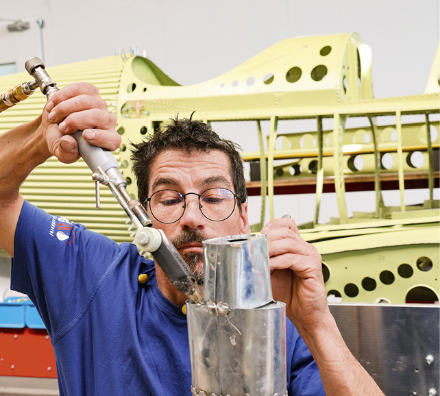 Vorne entsteht ein Flugzeugmodell. Im Hintergrund ist der Rumpf einer echten Junkers-Maschine zu sehen