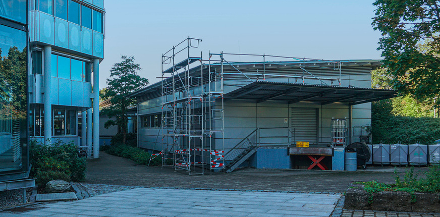 Das Kantinengebäude mit auskragendem Dachvorsprung ­befindet sich in einer Tallage. Bäume, Grünflächen sowie fast ganztägige Beschattung beeinflussen die Bauphysik