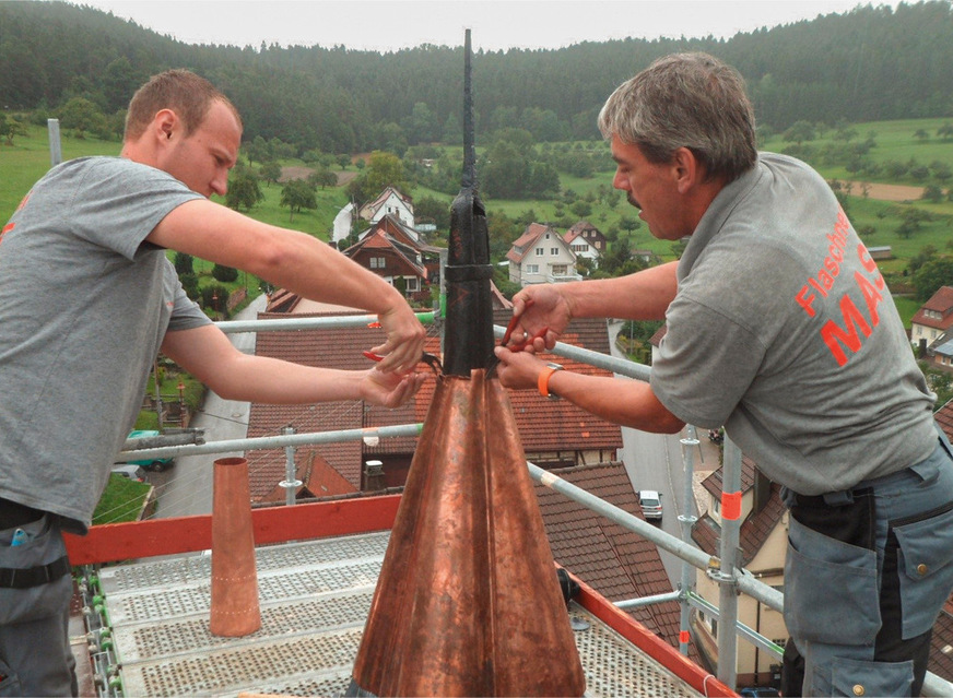 Thomas Renz und Peter Mast erledigen Sanierungsarbeiten an einer Turmspitze