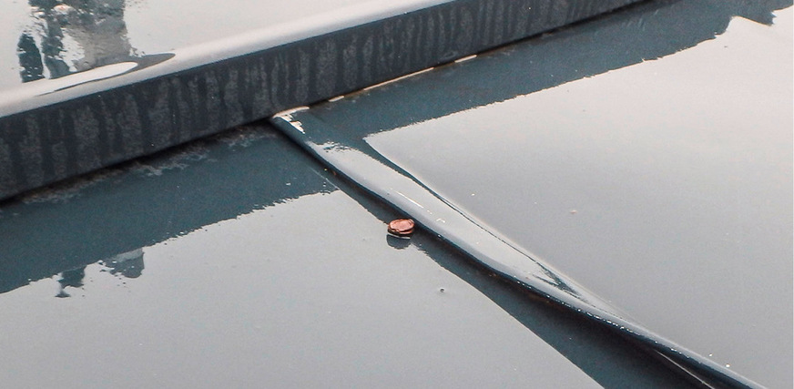 Kratzer und abgeplatzter Lack am umgelegten Stehfalz deuten auf eine massive Dehnungsbehinderung hin. Dass die direkt und sichtbar befestigte Dachrandabdeckung den umgelegten Falz direkt berührt, setzt der schlechten Ausführung die Krone auf