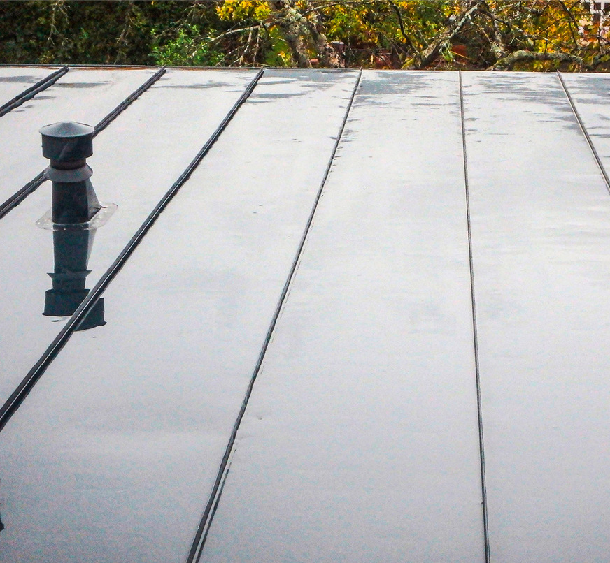 Vorher: Die regenfeuchte Oberfläche der Doppelstehfalzeindeckung lässt zahlreiche Verspannungen sichtbar werden