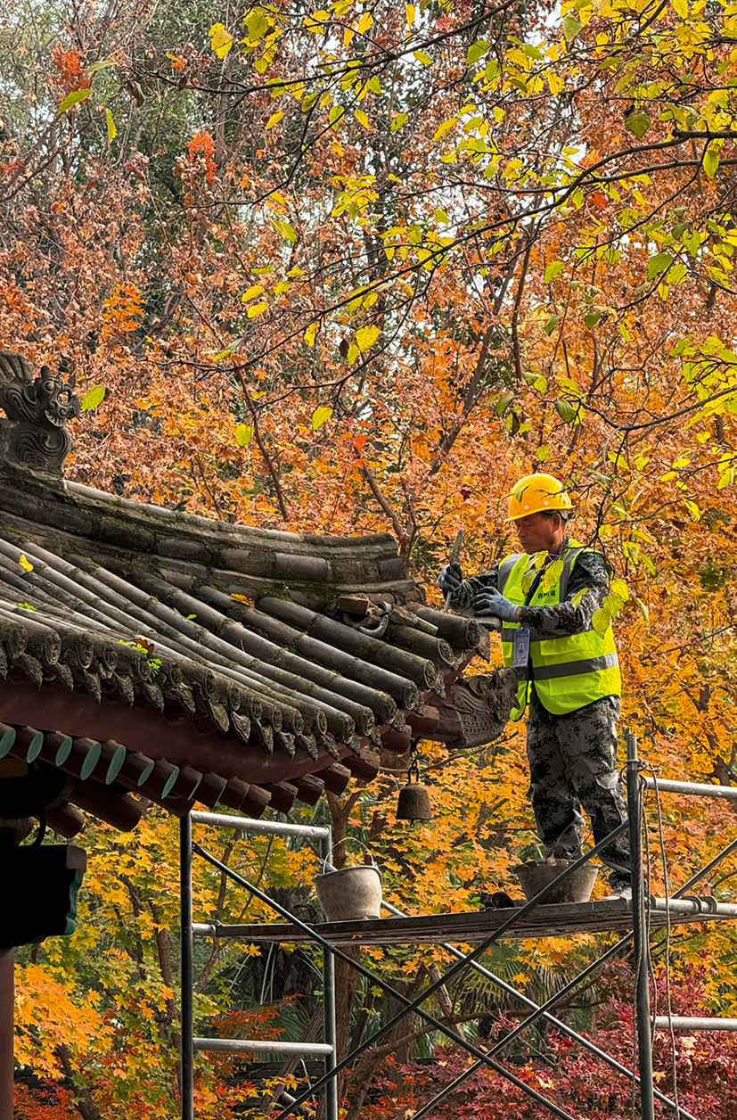 Ein Dachdecker repariert den Gratbereich eines hostorischen Daches