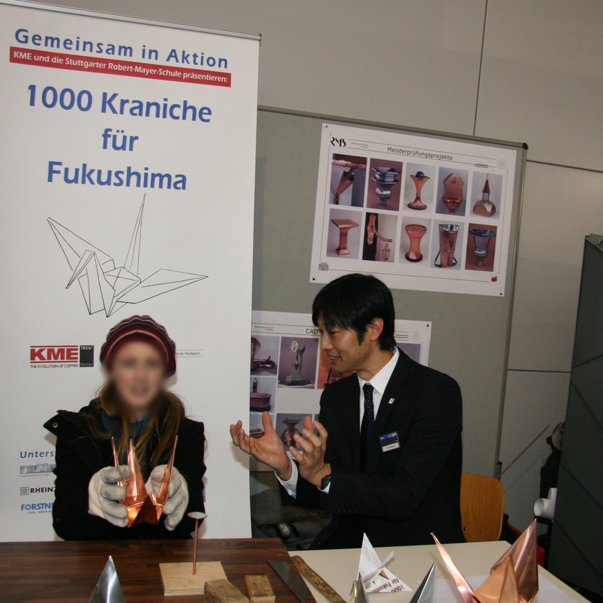 Auf der Dach+Holz lernt eine Schülerin das Kranichfalten von So Iwamoto