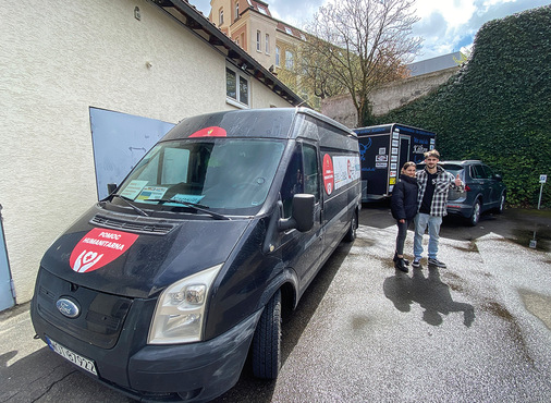 Innendesignerin Olga Sholomiy und Spenglermeister ﻿Patryk Muszalik nehmen vom Gentner-Verlagsteam Sachspenden entgegen. Darunter sind auch 100 Paar nagelneue Herrenschuhe