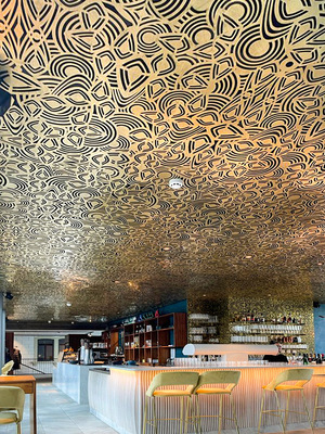 Links: Blick in die Bar und auf die ­Decke mit mustergeprägten ­Metallkassetten - © Bild: BAUMETALL
