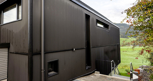 Auf den ersten Blick scheint die Fassade mit dunklen, geschuppten Holzleisten bekleidet zu sein