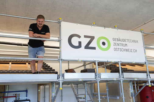 Marco Looser auf dem Trainingsgerüst. Unter den Modelldächern werden Heizungsbauer und Installateure beim Einbau technischer Anlagen geschult