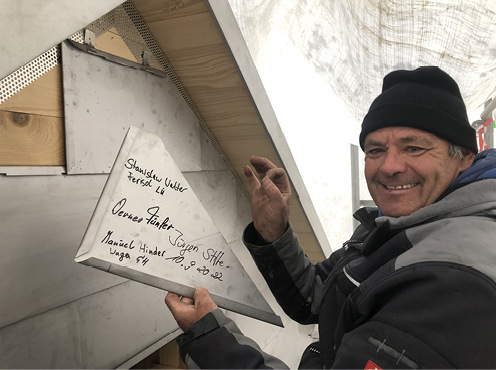    Einbau der letzten, vom Team signierten Fassadenschindel