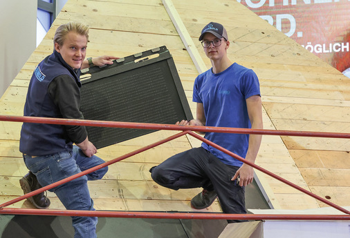  Thomas Reinbold montiert auf der Messe mit einem Auszubildenden Solardachplatten von Prefa - © Bild: BAUMETALL
