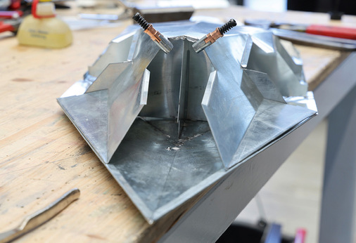 Zwei Fixierhilfen des Clipmaster-Sets und die dazu passende Zange (r.)