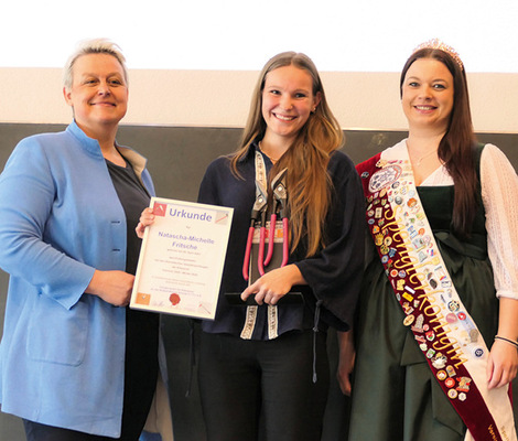 Handwerkskammerpräsidentin Katja Maier gratuliert Natascha-Michelle Fritsche zu ihrem herausragenden theoretischen Prüfungsergebnis. Spenglerkönigin Marion I. unterstützt sie dabei 