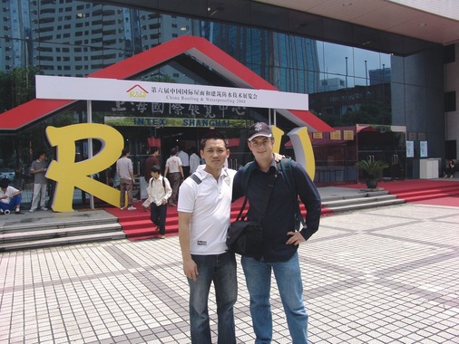 Tom Vilaysone von Rheinzink-Shanghai und Michael Schrodt vor dem Eingang zur Shanghaier “Dach+Holz“. Gemeinsam besichtigen sie Klempnerarbeiten an einem Schulgebäude, einem Einkaufszentrum sowie am Botschaftsgebäude der Republik Korea