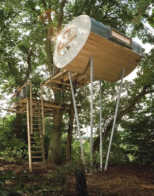 Die Form des Baumhauses Djuren erinnert an ein in der Längsachse aufgetrenntes Ei. Gesteigert wird diese Assoziation durch cremeweiße Acrylglas-Giebelflächen, in deren Mitte ein elliptisch geformtes Fenster Akzente setzt. Doch auch die Lage des Bau(m)-grundstückes beeindruckt. Es befindet sich am Ortsrand zwischen einzelnen freistehenden Wohnhäusern und mächtigen Eichen
