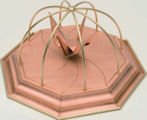 10 Kranich <br />Origamifigur auf Plateau mit geschwungenen Segmenten <br />Material: Kupfer / Messing Verbindung: Falz- und Falttechnik
