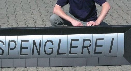 26 Werkstattschild Gewölbte Schriftfläche mit gegenläufig gewölbtem Rahmen Material: Farbaluminium / Titanzink Verbindung: Falztechnik