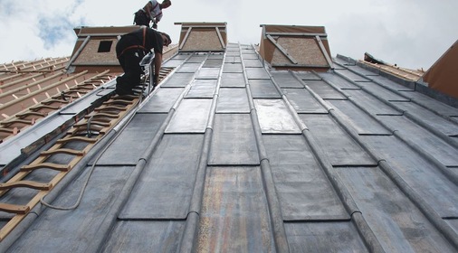 Die speziell angefertigten Dachleitern passen exakt zwischen die Wulste und bieten sicheren Halt. Selbstverständlich sind bei der 52° Dachneigung alle Mitarbeiter angeseilt
