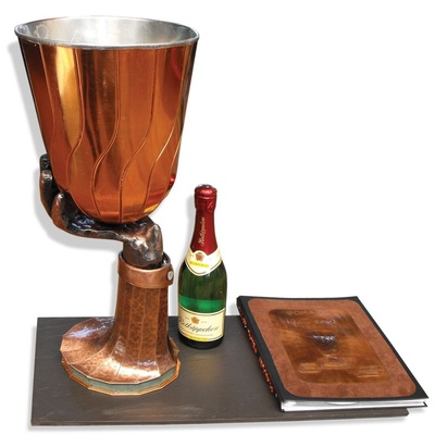 45 PokalDer Pokal aus geschwungenen Einzelsegmenten ruht auf einer getriebenen Hand, die wiederum auf einem aus gepolterten Segmenten hergestellten Sockel montiert istMaterial: Kupfer walzblank, verzinnt, gefärbt Verarbeitung: Falz-, Löt-, Treib- und Poltertechnik