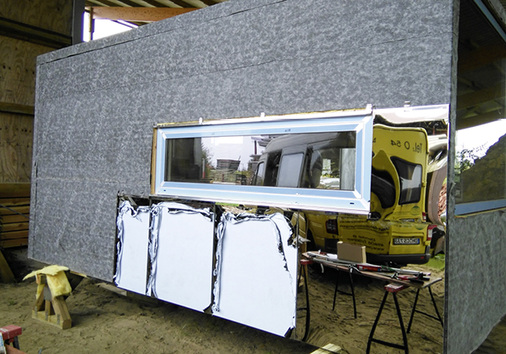 
In der Werkstatt entstand zunächst ein Holzrahmen, an dem Sperrholzplatten, Fenster und die Edelstahlfassade vormontiert wurden. Unter der verspiegelten Edelstahlfassade befestigten die Klempner eine Unterspannbahn
