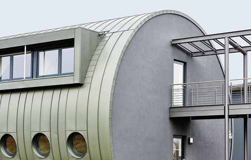 Fassadeneinteilung mit unterschiedlichen Bandbreiten: Die unteren Schare orientieren sich an der Position der Bullaugen, während die ungestörte Fläche oberhalb der Gauben Schare mit gleichmäßiger Breite erhielt. Rechts der Übergang zur Geschäftsführung