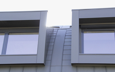 Details an den Gauben mit dezenter Entwässerung des Gaubendachs und mit der Schuppendeckung zur Aufnahme der thermischen Längenänderungen. Die Gauben wurden mit einem selbst entwickelten Steckleistensystem bekleidet