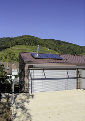 
Die rot-grün gestreifte Titanzinkfassade sowie die beiden gegeneinander gestellten roten Titanzink-Pultdächer des Schwarzwaldhauses fügen sich harmonisch in die Landschaft ein. Große Fensterflächen sowie gläserne Balkonbrüstungen erzeugen eine gewisse Transparenz und die Holzdielenbeläge auf den Freiflächen schlagen eine Brücke zur umliegenden Natur
