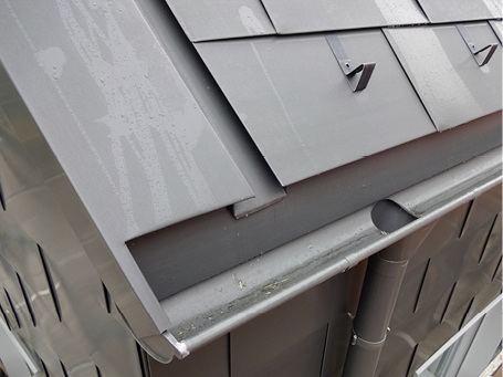 
Gut zu erkennen: die vertiefte Ortgangrinne, die halbrunde Dachrinne samt Stutzen und ein Schneestopp-Element 
