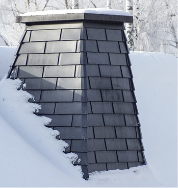 
Anthrazitfarbene Aluminiumtafeln mit kleinen Eckprofilen am Schornstein, der in Form eines Pyramidenstumpfes konstruiert wurde
