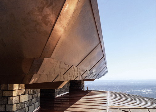 
Die Highlights am frisch verlegten Kupferdach: flach geneigte Stufenoptik und Doppelstehfalztechnik. Außerdem eine Bekleidung mit Faszien und extra große Schornstein-Abdeckungen
