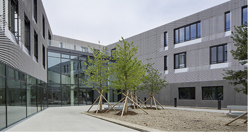 
Die U-Form des größeren Gebäudes umschließt einen begrünten Hof
