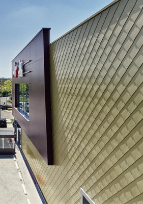 
Im Unterschied zu Platten oder Schindeln weisen Rauten Vor- und Rückkantungen auf, mit denen sie ineinandergehängt und dann befestigt werden. Es entsteht eine betont plastische Fassade, die mit der Sonneneinstrahlung lebendige Schattenspiele erzeugt
