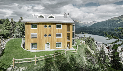 <p>
Eigenwillige Kombination: spitz zulaufende Dachgauben und Tür kombiniert mit hölzerner Fassade über dem Alpensee
</p>