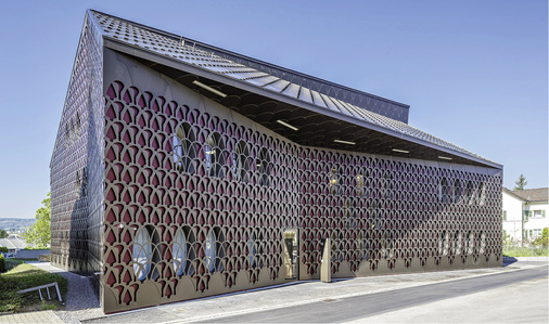 <p>
</p>

<p>
Hinter der filigranen Fassade aus eloxiertem Aluminium zeichnen sich die darunterliegende Fassadenebene und die ovalen Fenster ab
</p> - © Foto: www.zuegerpix.ch


