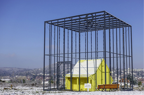 <p>
</p>

<p>
Wie ein riesiger Vogelkäfig schützt ein Gitter das bedrohte Haus
</p> - © BAUMETALL

