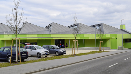 



Grüntöne der Fassade und das Grau der Titanzinkeindeckung sowie des Pflasterbelages bestimmen das Erscheinungsbild der modernen Sporthalle 
