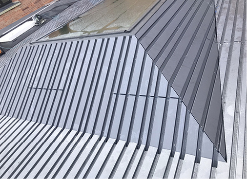 
Die teilperforierte Bekleidung auf dem Gebäude. Damit die Profilgeometrie über die Auffaltung hinweg erhalten bleibt, wurden einige Hochsicken gestreckt



