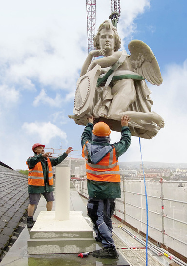 Der restaurierte und im Farbton des verwitterten Sandsteins gestrichene Engel wird auf dem Giebel des Hauptbahnhofs auf seine neue Verankerung gesetzt