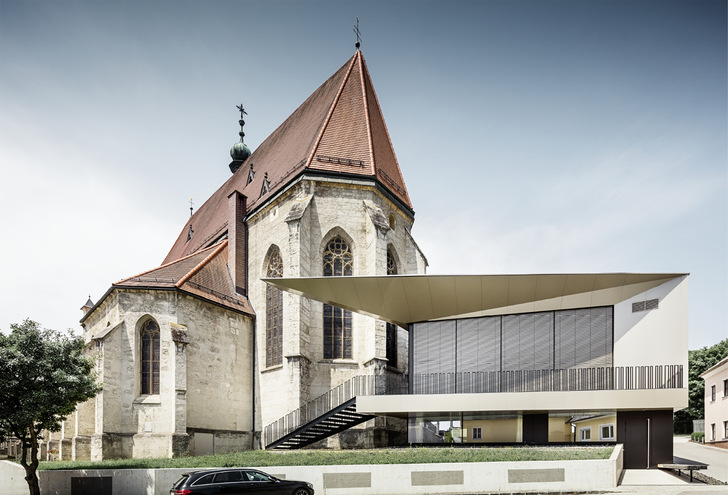 Frech schiebt sich der futuristische Neubau vor die alte Pfarrkirche