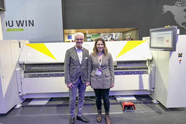 RAS-Geschäftsführer Willy Stahl mit BAUMETALL-Onlineredakteurin Laura Kornhaaß vor der Flexi2Bend am RAS-Messestand auf der Euroblech