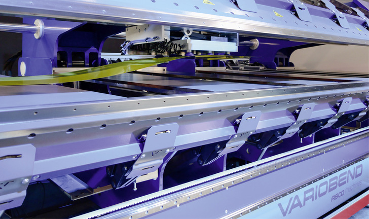 Zuvor zugeschnittene Blechstreifen werden von der Seite automatisch in die Maschine eingezogen